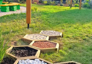 Ścieżka sensoryczna wypełniona otoczakami, korą, szyszkami, drobnym żwirkiem, kasztanami i piaskiem.